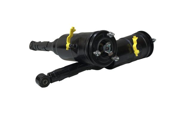Two black shock absorbers with yellow mounting bolts on a white surface.